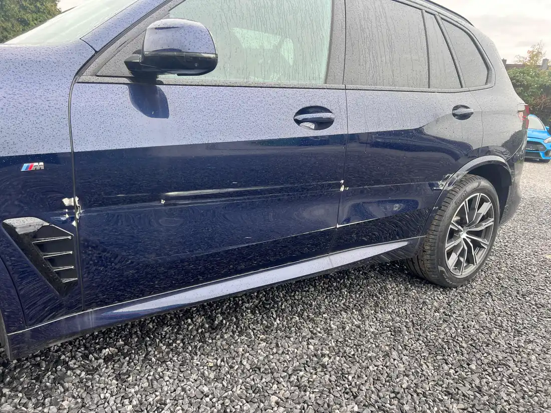 Blauer BMW X5 mit Dellen und Kratzern an Fahrer- und Hintertür