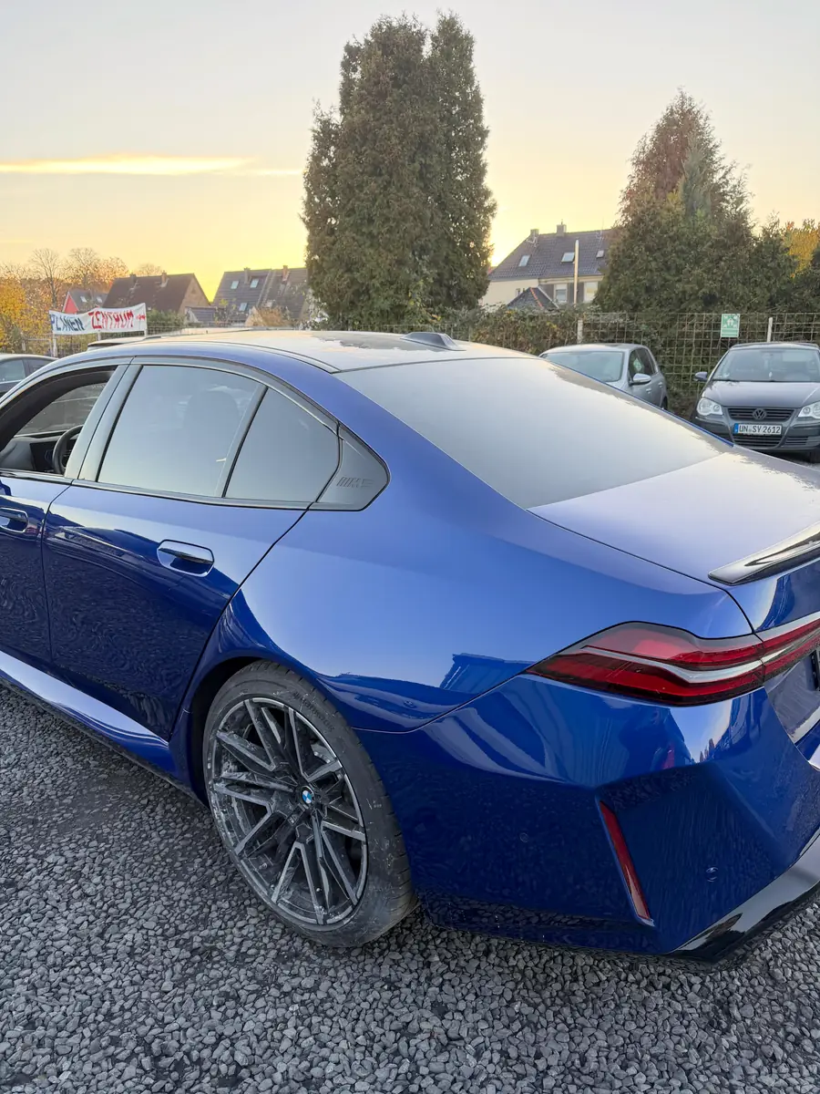 Derselbe BMW 5er fertig lackiert auf dem Hof im Abendlicht