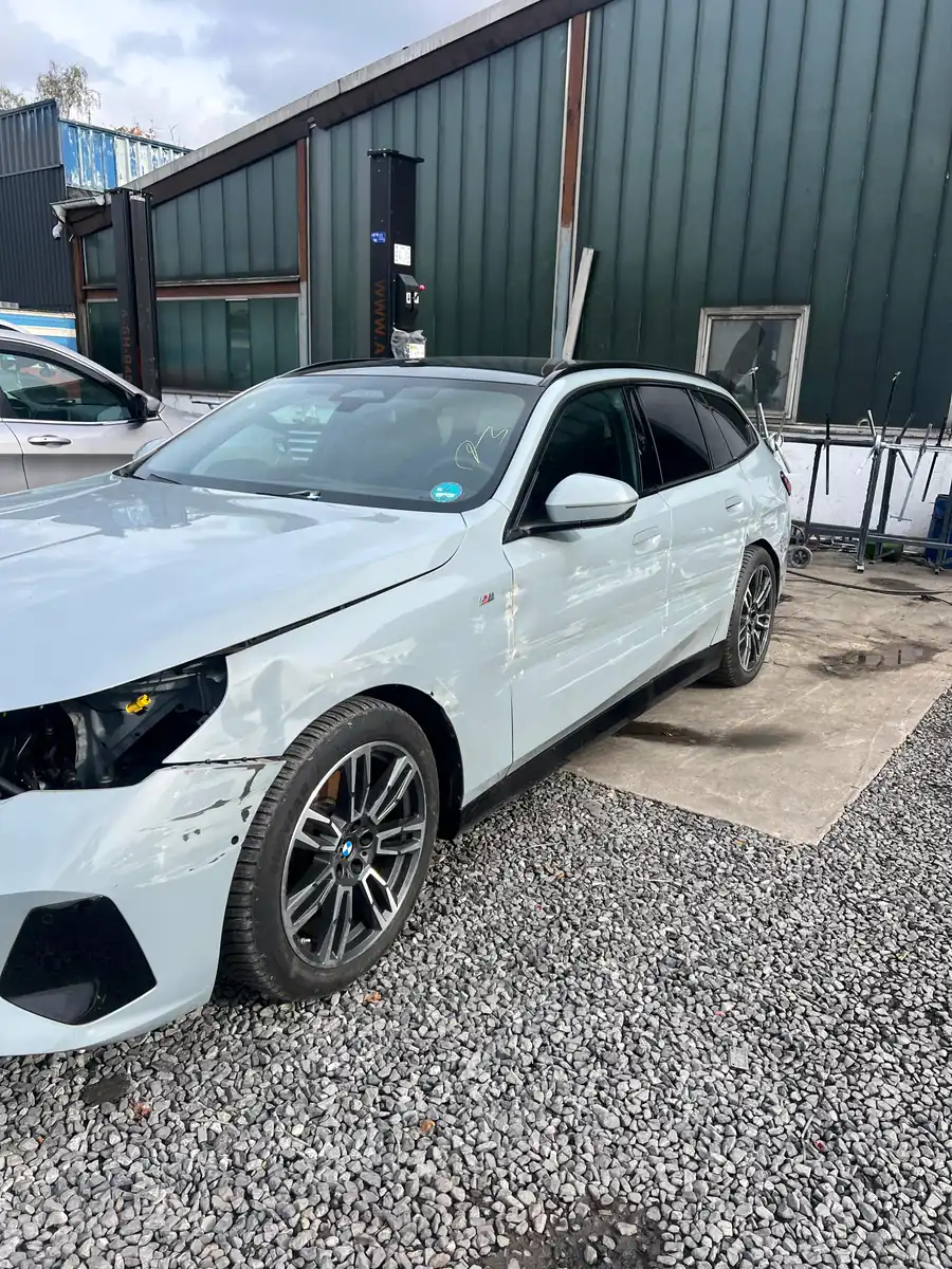 Weißer BMW 5er Touring mit Frontschaden bei der Annahme auf dem Hof